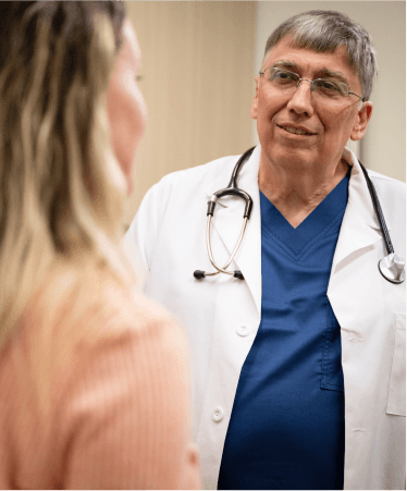 Optum OR doctor in a white coat and stethoscope talking with a patient