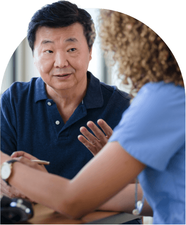 Male patient in a discussion with a healthcare professional in blue scrubs